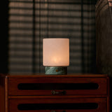 Cuyp Small rechargeable table lamp in Ice Green marble glowing on a vintage wood dresser at dusk