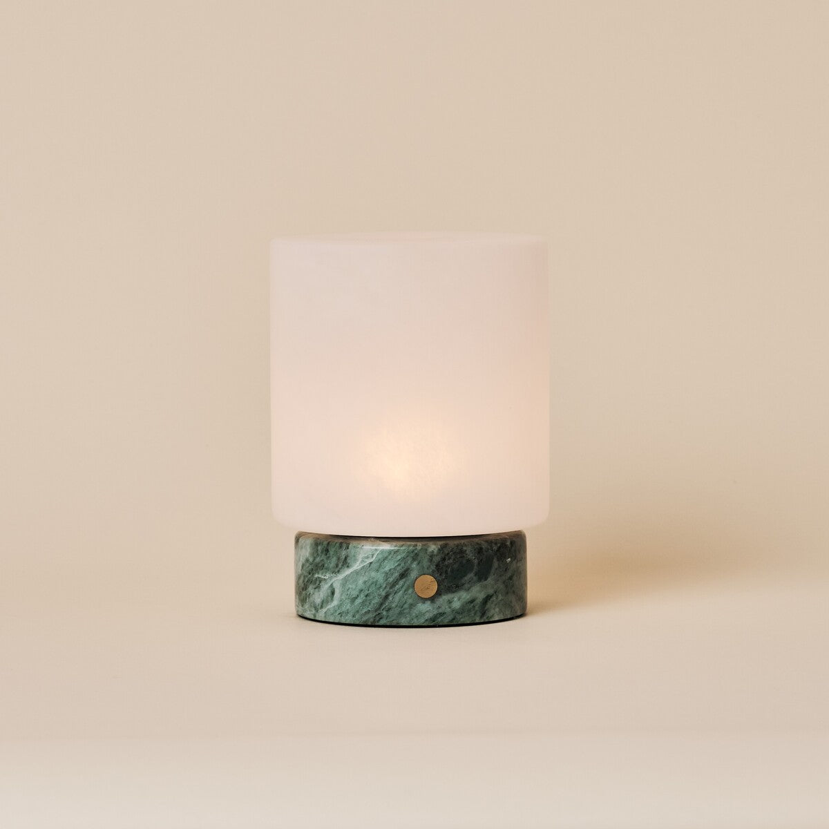 Cuyp Small rechargeable table lamp in Ice Green marble glowing on a plain beige studio backdrop