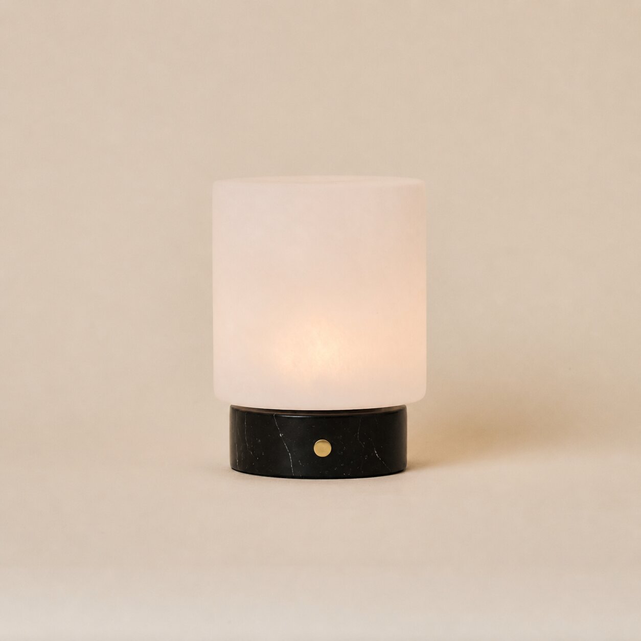 Cuyp cordless table lamp with Nero Marquina black marble base and frosted glass shade on beige backdrop