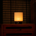 Cuyp cordless table lamp with black marble base glowing on a wood dresser against woven blinds