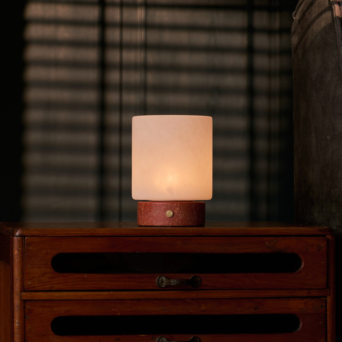 Lampe de table Cuyp Small travertin rouge rechargeable Tavellio - sur une table de chevet, ombres de store vénitien en arrière-plan