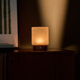 Lampe de table Cuyp Small travertin rouge sans fil Tavellio - allumée sur un meuble en bois près d'un cadre à rayures