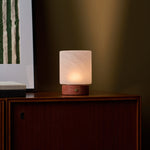 Lampe de table Cuyp Small travertin rouge rechargeable Tavellio - allumée sur un meuble ancien en bois dans une pièce sombre