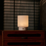 Cuyp Small Rosa Aurora lampe de table rechargeable Tavellio – sur une commode sombre le soir, ombres rayées d'un store projetées au mur