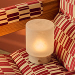 Cuyp Small Rosa Aurora lampe de table sans fil Tavellio – nichée dans un fauteuil à motifs rouge et crème, ambiance chaleureuse