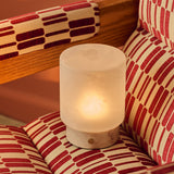 Cuyp Small Rosa Aurora lampe de table sans fil Tavellio – nichée dans un fauteuil à motifs rouge et crème, ambiance chaleureuse
