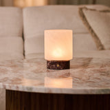 Cuyp rechargeable table lamp in Rosso Levanto marble reflected on a marble table beside a beige sofa