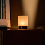 Tavellio Cuyp lamp with Rosso Levanto marble base radiating warm light on a wooden sideboard at dusk