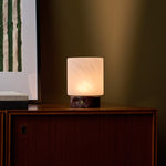 Cuyp cordless table lamp with red marble base on a wood cabinet against an olive green wall