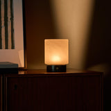 Tavellio Cuyp Small cordless table lamp in Verde Alpi marble lit beside striped wall art on a wood cabinet