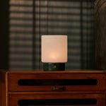 Cuyp Small cordless table lamp in Verde Alpi marble casting warm light with striped blinds shadow behind