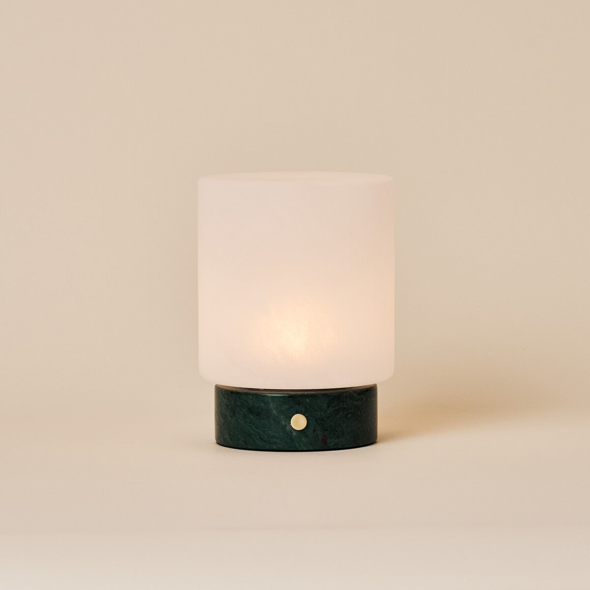 Cuyp Small rechargeable table lamp in Verde Alpi green marble glowing on a plain beige studio backdrop