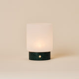 Cuyp Small rechargeable table lamp in Verde Alpi green marble glowing on a plain beige studio backdrop