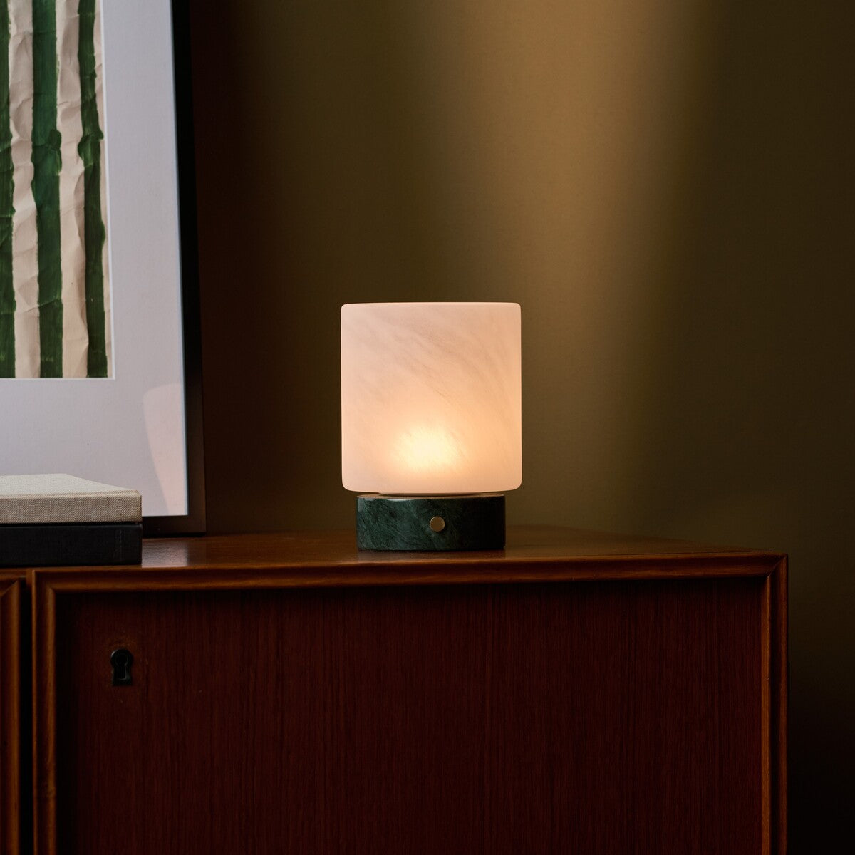 Cuyp Small rechargeable table lamp in Verde Alpi marble on a wood cabinet against an olive green wall