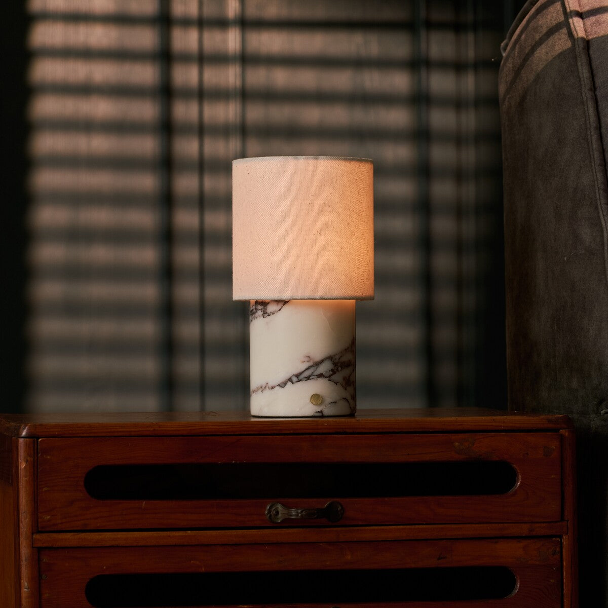 Dou Calacatta Vionaro lampe de table rechargeable Tavellio – sur une commode en bois – plaid à rayures roses posé à côté