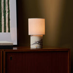 Dou Calacatta Vionaro lampe de table rechargeable Tavellio – posée sur une enfilade en bois – affiche à rayures vertes en arrière-plan
