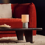 Tavellio Dou cordless table lamp on a dark coffee table beside a rust velvet sofa, Blue Calcite marble base