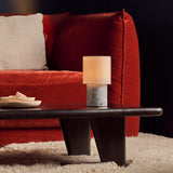 Tavellio Dou cordless table lamp on a dark coffee table beside a rust velvet sofa, Blue Calcite marble base