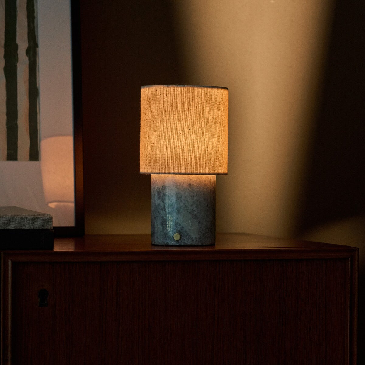 Dou cordless table lamp glowing on a dark bedroom nightstand, Blue Calcite marble base with white veining