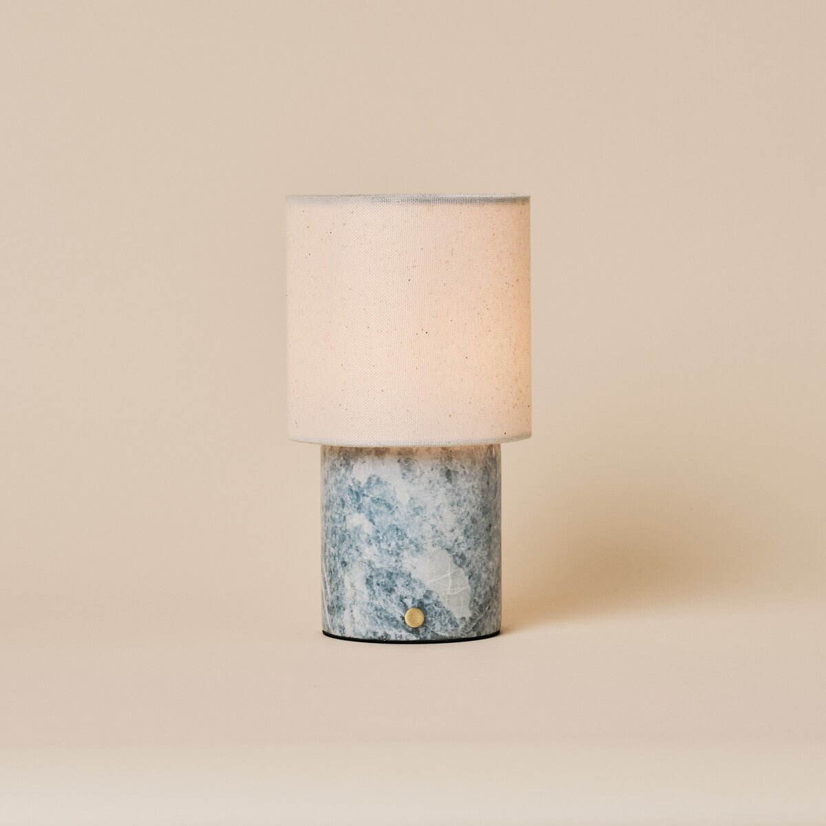 Dou rechargeable table lamp in Blue Calcite marble with a cream linen shade, studio shot
