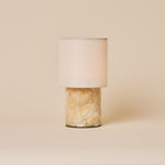Dou cordless table lamp in Honey Onyx marble with a cream linen shade, studio shot