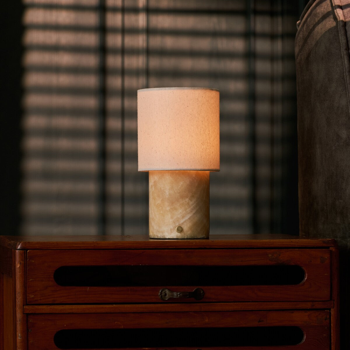 Dou rechargeable table lamp beside a striped throw blanket on a wood dresser, golden Honey Onyx marble base