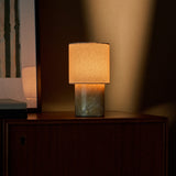 Tavellio Dou cordless table lamp glowing on a dark bedroom nightstand, Honey Onyx marble base