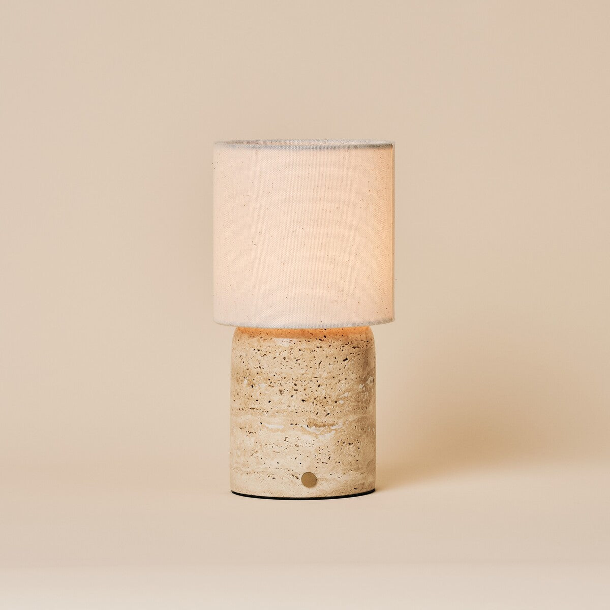 Cordless table lamp Dou Large Classic Travertine with a cream linen shade on a plain studio backdrop