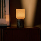 Dou Large cordless table lamp glowing warmly on a wood cabinet beside framed striped art