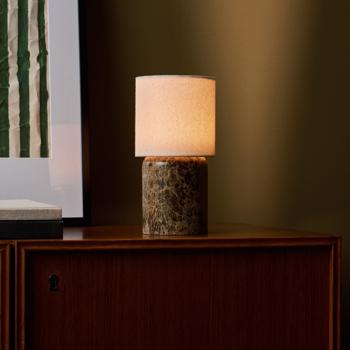 Tavellio Dou Large cordless table lamp with linen shade glowing on a wood sideboard near framed art
