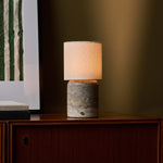 Tavellio Dou Large Silver Travertine table lamp beside a green striped art print on a cabinet