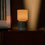 Rechargeable table lamp Dou Large Silver Travertine glowing warmly on a dark wood sideboard at dusk