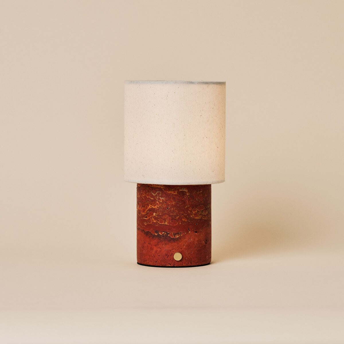 Dou Red Travertine rechargeable table lamp with natural linen shade on a warm beige backdrop
