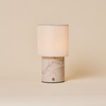 Dou Rosa Aurora lampe de table sans fil Tavellio – photo studio sur fond beige – marbre rose pâle veiné de corail