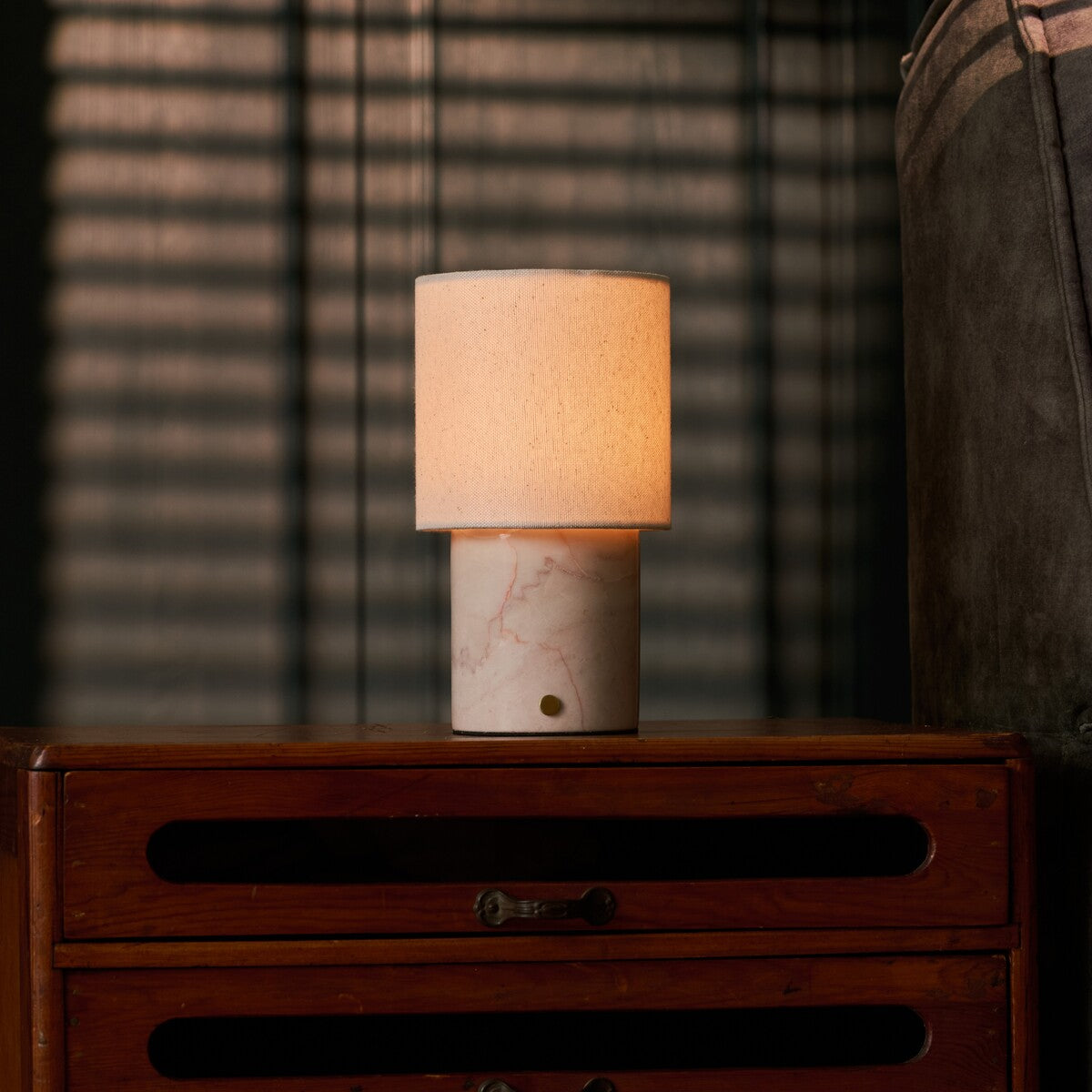 Dou Rosa Aurora lampe de table sans fil Tavellio – sur une commode en bois – store vénitien projetant des ombres en lignes