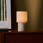 Dou Rosa Aurora lampe de table rechargeable Tavellio – sur une commode en bois – affiche à rayures vertes en arrière-plan