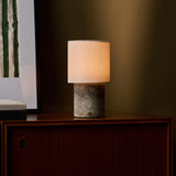 Dou Silver Travertine lampe de table sans fil Tavellio – allumée sur une enfilade en bois au crépuscule – mur vert olive en arrière-plan