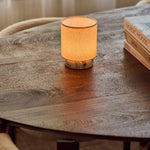 Dou Small Arabescato Marble Rechargeable Table Lamp lit on a wooden table next to a stack of design books