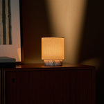 Dou Small Arabescato Marble Rechargeable Table Lamp lit on a dresser beside a soft pink throw blanket