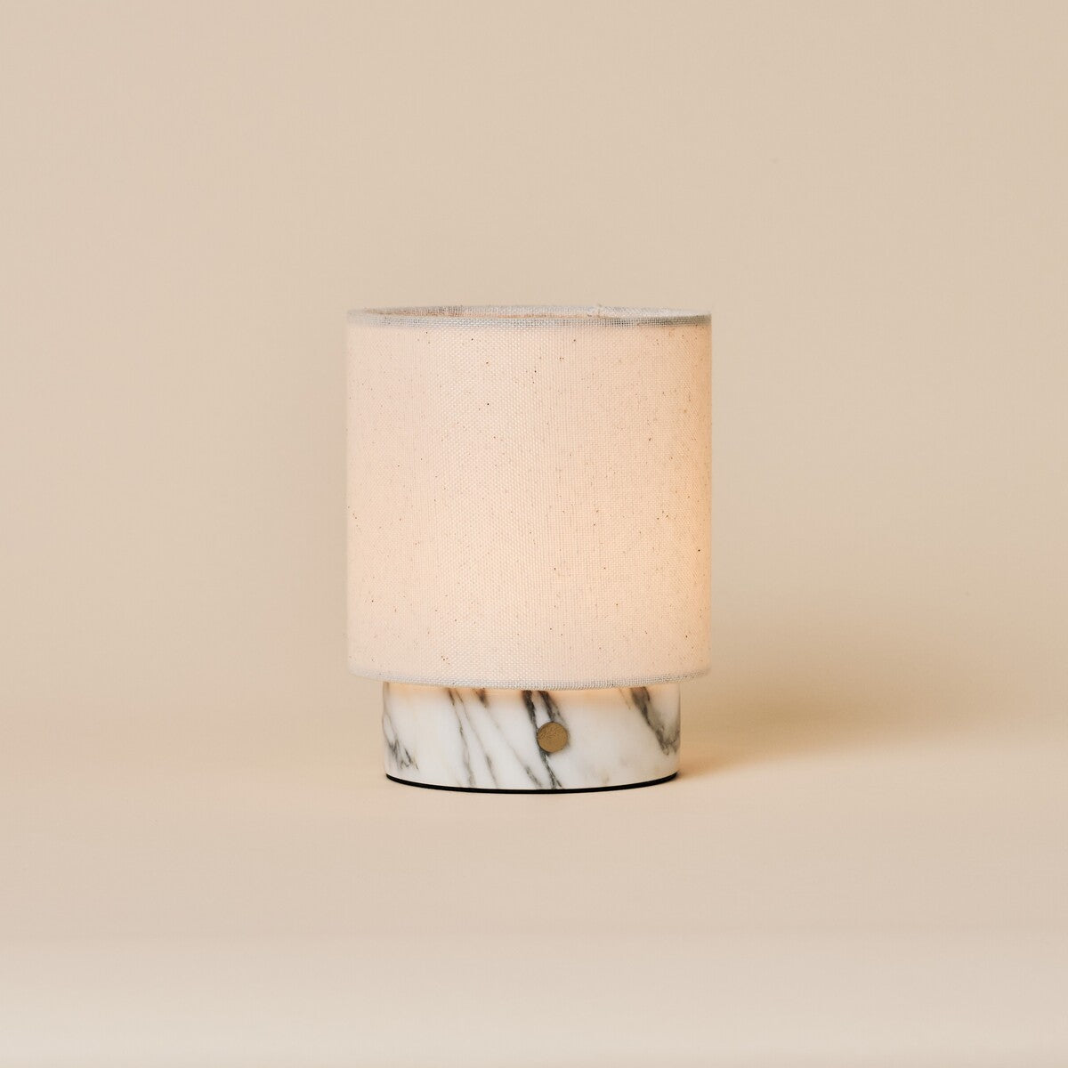 Dou Small Arabescato Marble Rechargeable Table Lamp with a cream linen shade on a neutral studio backdrop