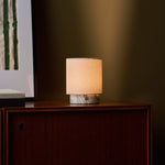 Tavellio Dou Small Arabescato Marble Rechargeable Table Lamp lit on a walnut cabinet beside framed wall art