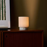 Dou Small rechargeable table lamp in Bianco Statuarietto marble glowing on a wood sideboard at night