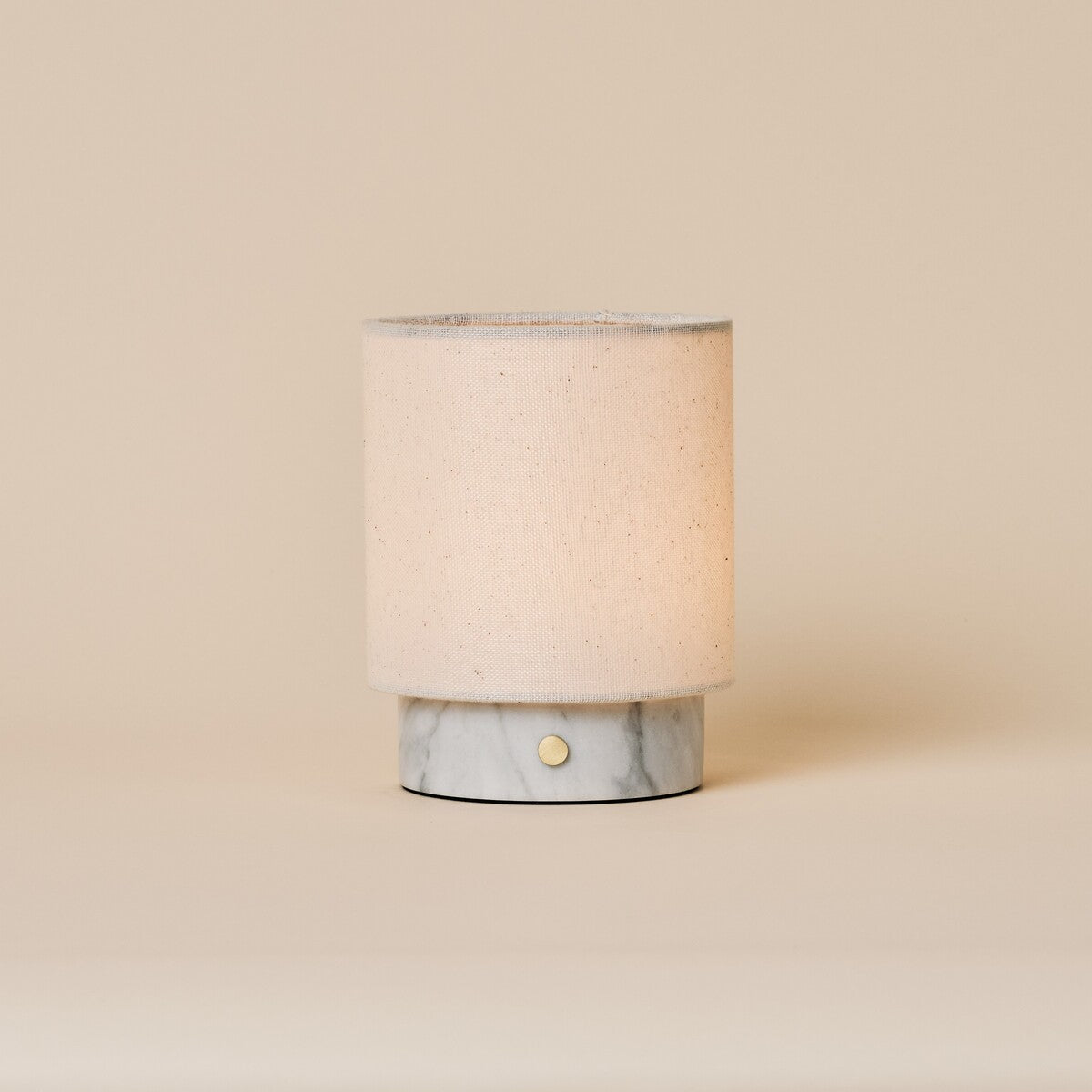 Rechargeable table lamp Dou Small in Bianco Statuarietto marble with natural linen shade on beige backdrop