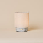 Rechargeable table lamp Dou Small in Bianco Statuarietto marble with natural linen shade on beige backdrop