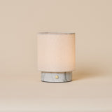 Rechargeable table lamp Dou Small in Bianco Statuarietto marble with natural linen shade on beige backdrop