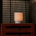 Dou Small rechargeable table lamp, Bianco Statuarietto marble base, glowing atop a vintage chest of drawers