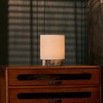 Dou Small rechargeable table lamp in Calacatta Viola marble glowing atop a vintage chest of drawers