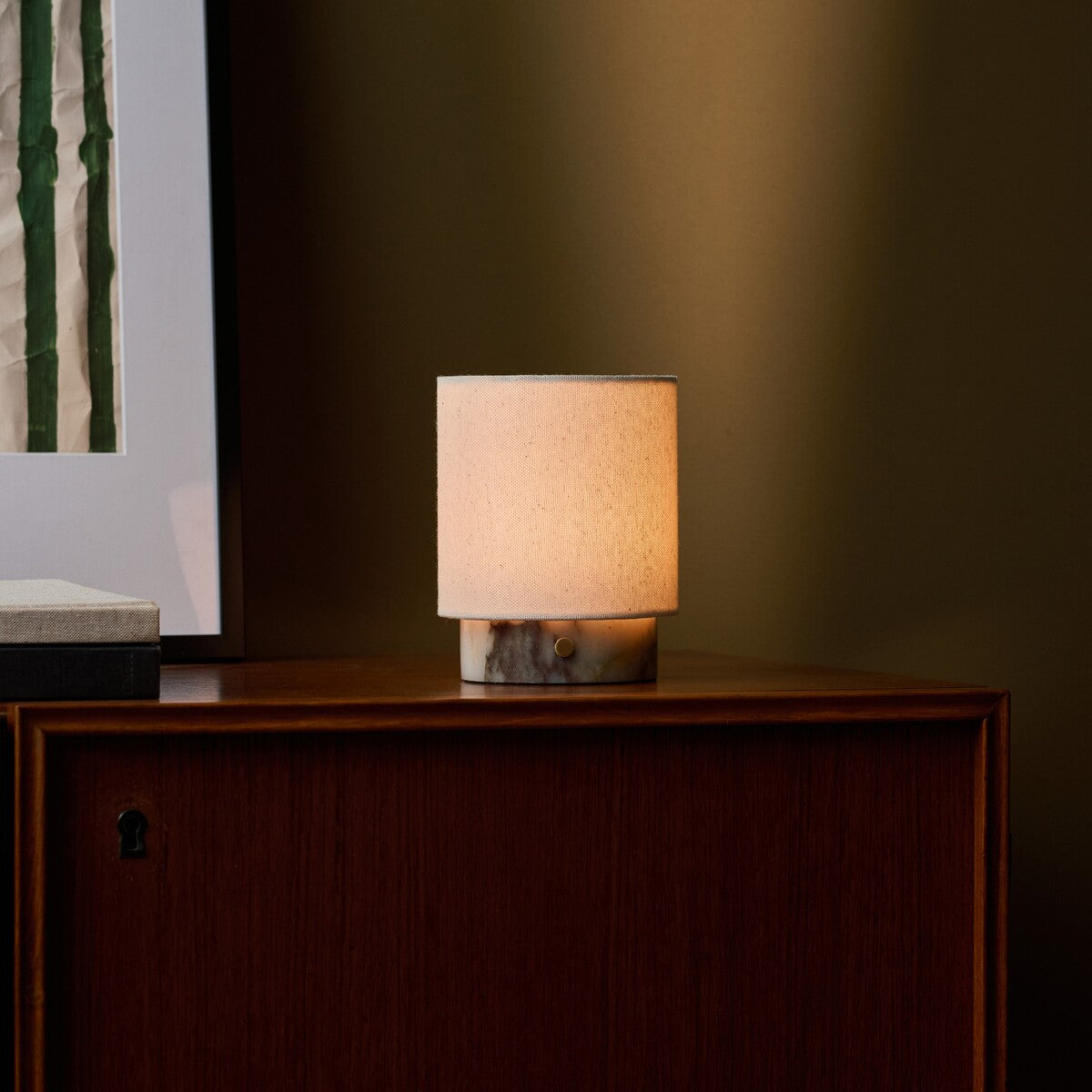 Dou Small rechargeable table lamp in Calacatta Viola marble glowing on a wood sideboard at night