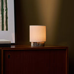 Dou Small rechargeable table lamp in Calacatta Viola marble glowing on a wood sideboard at night