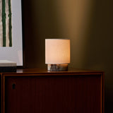 Dou Small rechargeable table lamp in Calacatta Viola marble glowing on a wood sideboard at night
